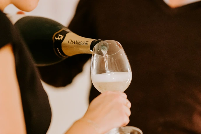 personne tenant une bouteille étiquetée noire versant dans un verre clair
